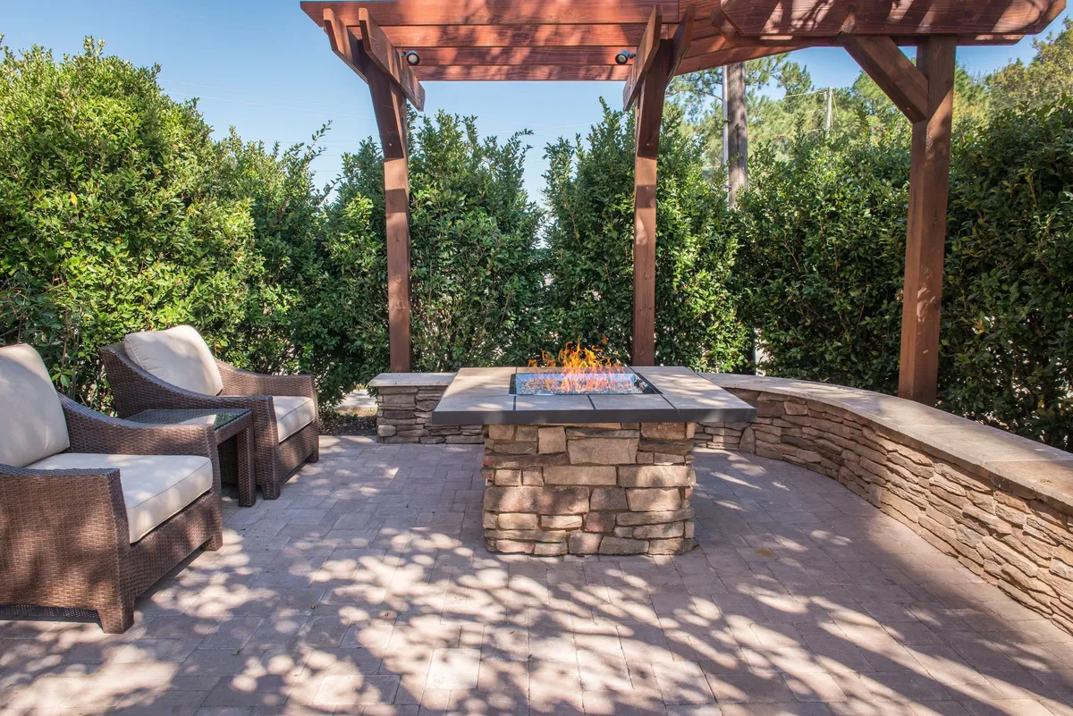 An inviting outdoor seating area centered around a fire pit, topped with a pergola. The space is designed for relaxation, socializing, and enjoying evenings outdoors, suggesting opportunities for guests to unwind after busy days exploring the area.