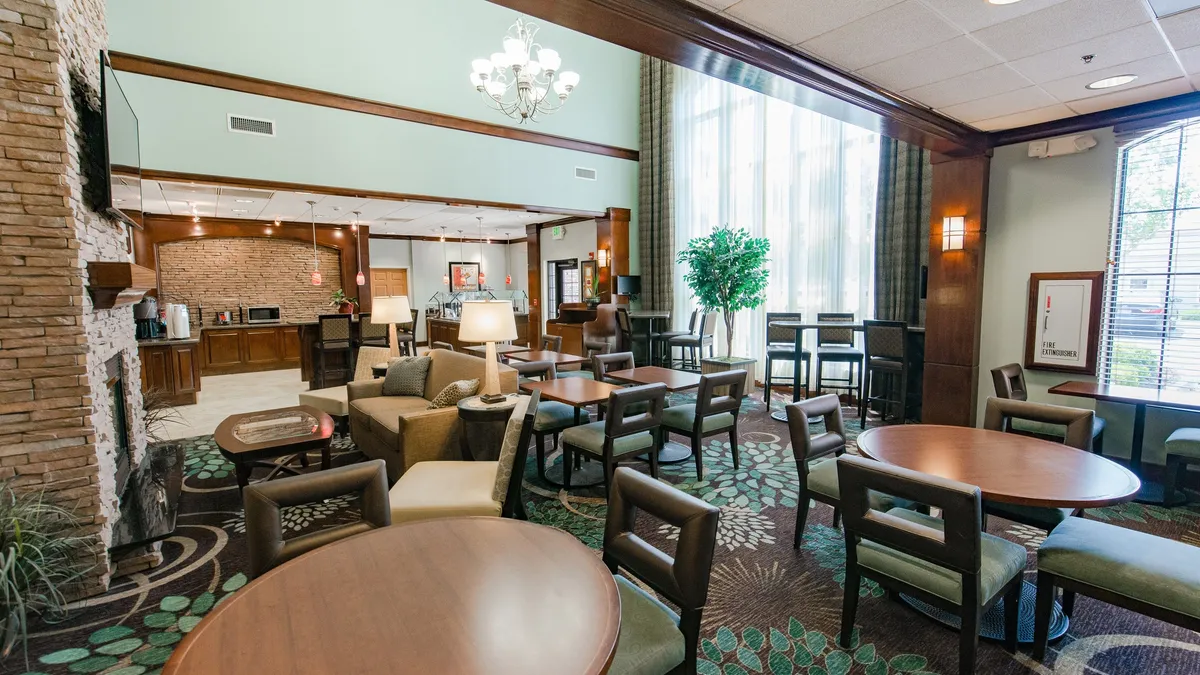 This image showcases a cozy studio living area with comfortable seating, large windows providing abundant natural light, a fireplace, and an adjacent dining area. The atmosphere is warm and inviting, perfect for relaxing after a day exploring or spending quality time with family.