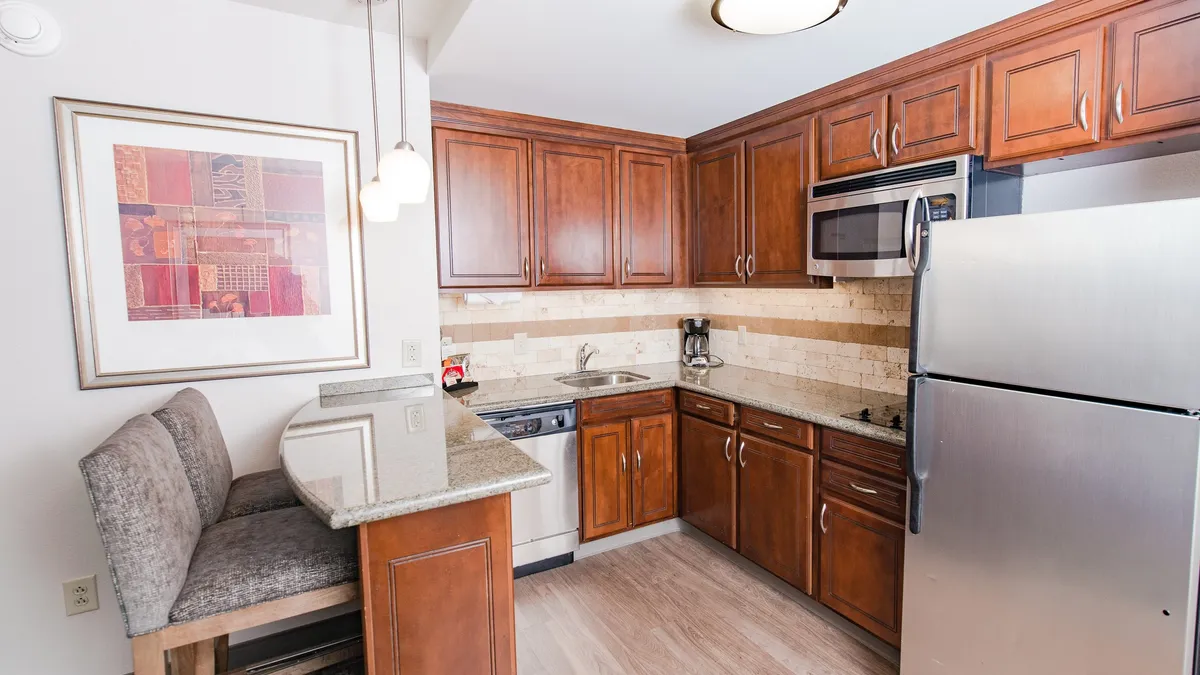 A modern studio kitchen and breakfast bar with granite countertops, stainless steel appliances, and chic cabinetry. The setting is cozy yet functional, inviting guests to enjoy meals or snacks at any time of day.